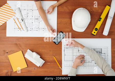 Above view of hands of creative architects pointing at smartphone with sketch Stock Photo