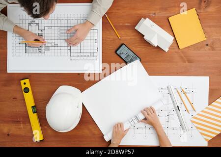 Overview of hands of two young contemporary engineers working over new sketches Stock Photo
