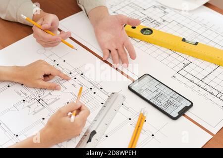 Hands of two young engineers with pencils over sketches of new construction Stock Photo