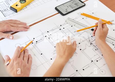Hand of young female engineer with pencil pointing at sketch of new building Stock Photo