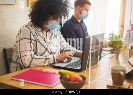 Young creative people working in modern workplace wearing protective masks - Focus on woman hand Stock Photo