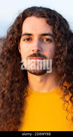 Vertical shot of a young man with long curly hair Stock Photo