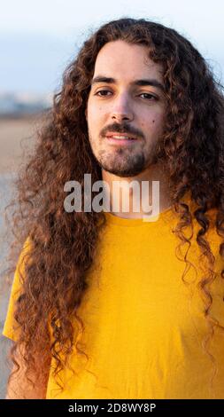 Vertical shot of a young man with long curly hair Stock Photo