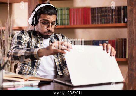 Positive Indian Student Guy At Laptop Learning Online At Home Stock Photo