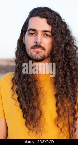 Vertical shot of a young man with long curly hair Stock Photo