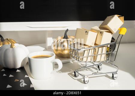 Workplace mock up concept. Modern home decor desktop computer with autumn decorations. Paper boxes in a trolley on the desktop. Online shopping Stock Photo