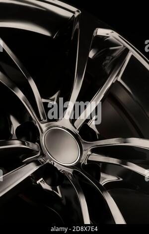 Black Gloss alloy wheel on a dark background. Stylish and expensive. Close-up of spoke elements, vertical photo, Stock Photo