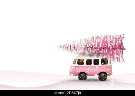 Toy bus car carries a Christmas tree from the forest. Pink and white colors, winter holiday new year mood Stock Photo