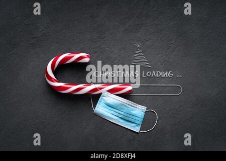 Christmas loading Concept - Candy cane on blackboard with christmas tree and surgical mask Stock Photo