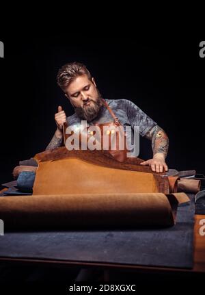 Skinner working with leather using crafting tools in the place of work Stock Photo