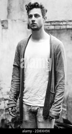 Grayscale portrait of a young male wearing a white t-shirt with a jacket outdoors Stock Photo