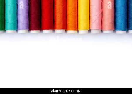 Colorful sewing threads on white background, top view. Spools of thread in different colors. Stock Photo