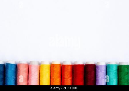 Colorful sewing threads on white background, top view. Spools of thread in different colors. Stock Photo