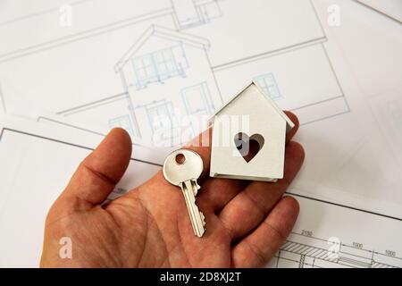 A hand holding house key and toy house as a symbol of new house idea. Stock Photo