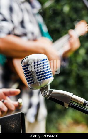 Vintage microphone with latin musician playing a guitar at the background at the street in Mexico Stock Photo