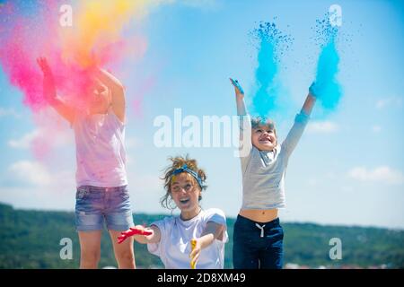 Excited children painted in the colors of Holi festival. Kids splashing colorful paint. Stock Photo