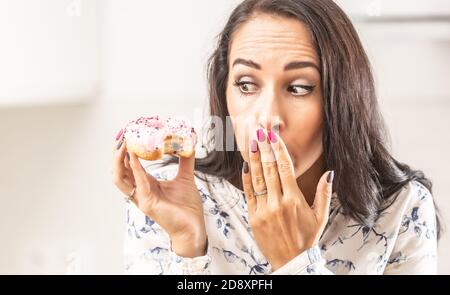 Oops expression on a face of a woman who has bitten into a donut in her hand. Stock Photo