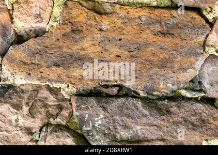 Ancient damaged rock wall of an abandoned house closeup for abstract background Stock Photo