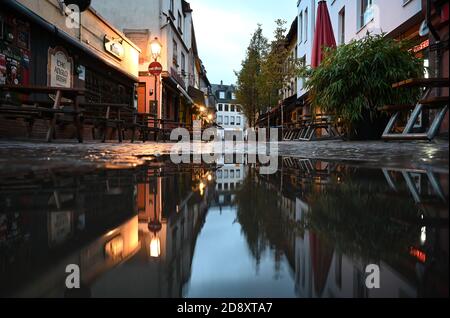 02 November 2020, Hessen, Frankfurt/Main: Closed pubs in the deserted Kleine Rittergasse in Alt-Sachsenhausen are reflected in a puddle in the early morning. A four-week partial lockdown has begun all over Germany to slow down the spread of the coronavirus. Photo: Arne Dedert/dpa Stock Photo