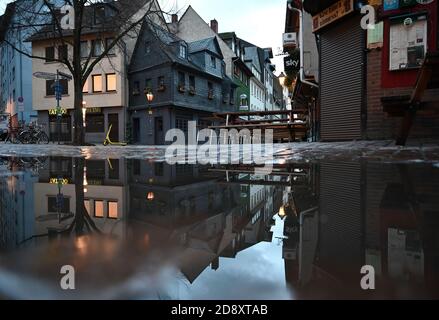 02 November 2020, Hessen, Frankfurt/Main: Closed pubs in the deserted Kleine Rittergasse in Alt-Sachsenhausen are reflected in a large puddle in the early morning. A four-week partial lockdown has begun all over Germany to slow down the spread of the coronavirus. Photo: Arne Dedert/dpa Stock Photo