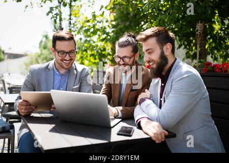 Group of attractive young business men colleagues working together in cafe Stock Photo