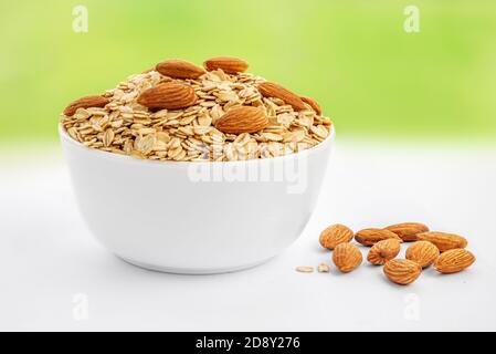 Oatmeal breakfast with almond nuts in bowl on a spring blurry  background. Healthy food concept Stock Photo