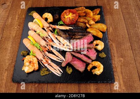 Surf and turf meal with sirloin steak, langoustine and tiger prawns Stock Photo