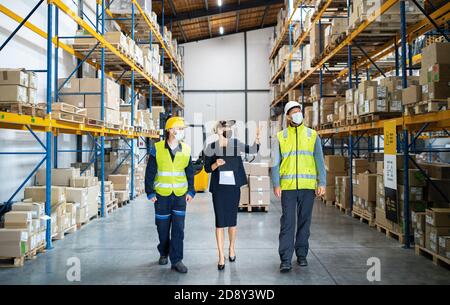 Group of workers with manager working indoors in warehouse, coronavirus concept. Stock Photo