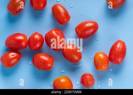 A group of cherry tomatoes isolated on a blue background. A group of fresh cherry tomatoes stacked and isolated on a blue background. Stock Photo