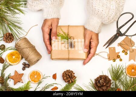 Woman holding a christmas package on a white table in a top view Stock Photo