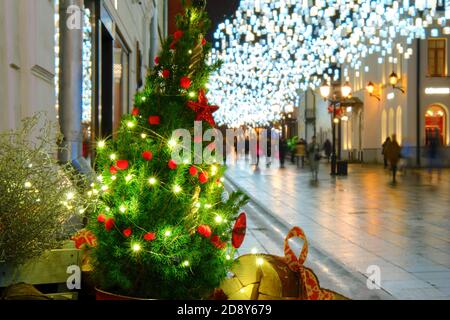 Street with shops decorated with Christmas trees with balls for the new year Stock Photo