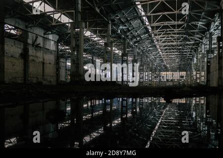 Inside of flooded dirty abandoned ruined industrial building with water reflection Stock Photo
