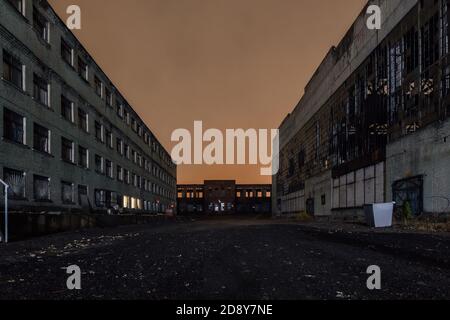 Territory of abandoned industrial area waiting for demolition at night. Broken and burnt buildings Stock Photo