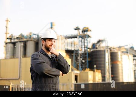 Portrait of thoughtful industrial engineer standing near factory outside. Stock Photo