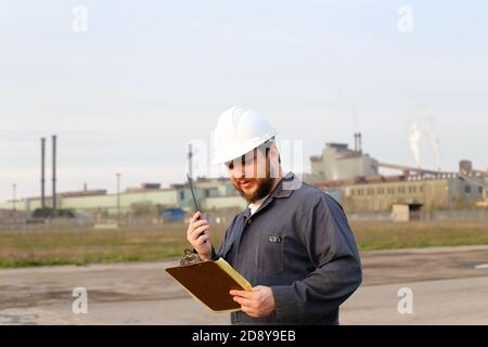 Foreman engineer standing on construction site and holding papers. Stock Photo