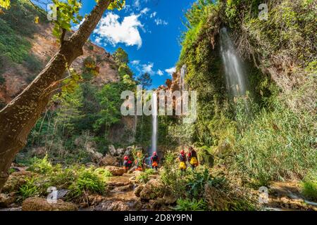 Unrecognizable people enjoy waterfall descent using ropes Stock Photo