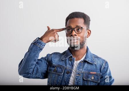 Shot of serious tired attractive black man shooting in temple with index finger, demonstrating suicide gesture, pretending killing himself wearing den Stock Photo