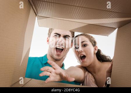 Couple opening cardboard box very happy with what's inside the box. Stock Photo