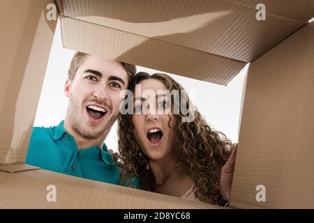Couple opening cardboard box very happy with what's inside the box. Stock Photo