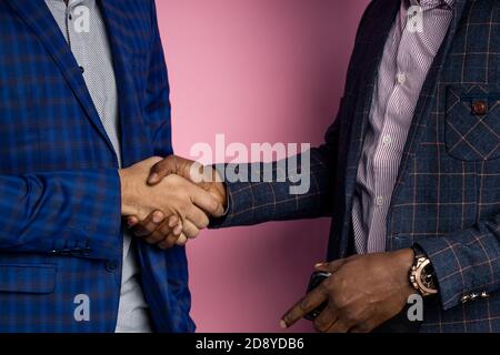 Closeup cropped shot of two multiethnic businesspeople wearing suits, shaking hands after signing good contract, congratulating each other, standing o Stock Photo