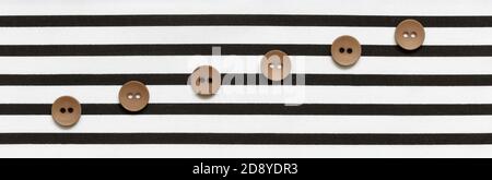 Buttons on the striped fabric in the form of a stave Stock Photo