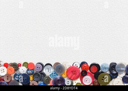 Multi-colored buttons on a white woven background in the form of a frame. Stock Photo