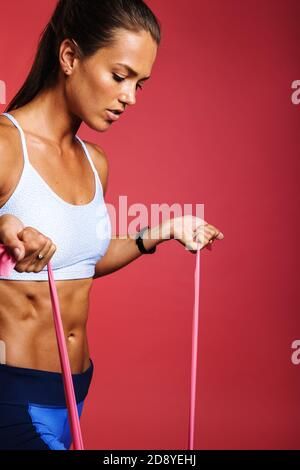 Close up of fitness woman doing fitness training using resistance bands. Female athlete working on muscle training using stretch bands. Stock Photo