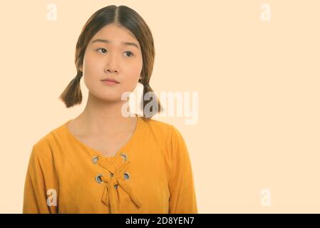 Studio shot of young beautiful Asian woman thinking Stock Photo