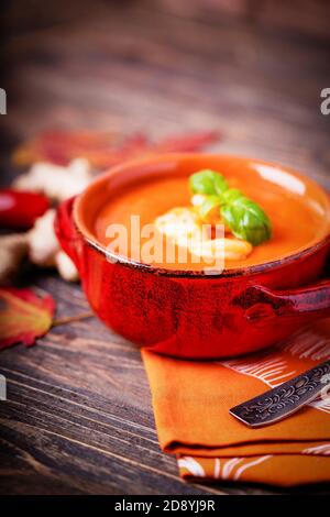 Homemade tomato soup with ginger, shrimps and basil on a brown wooden background, copy space Stock Photo