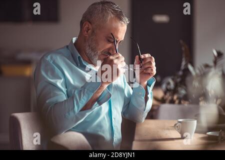 Middle aged bearded man putting on his eyeglasses Stock Photo