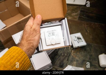 Paris, France - Oct 25, 2020: Man hand holding unboxing new modern with display Vaillant Ambisense VR51 room thermostat connected IoT device to the gas heating pump boiler Stock Photo