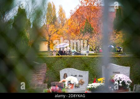 Strasbourg, France - Nov 1, 2020: View through fence of cemetry in France on All Saints Day during the second wave of the Coronavirus - people walking near tombes Stock Photo