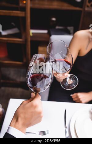 Cropped view of couple toasting with wine during dating in restaurant Stock Photo