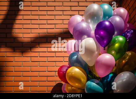 Bunch of colorful balloons against brick wall background Stock Photo